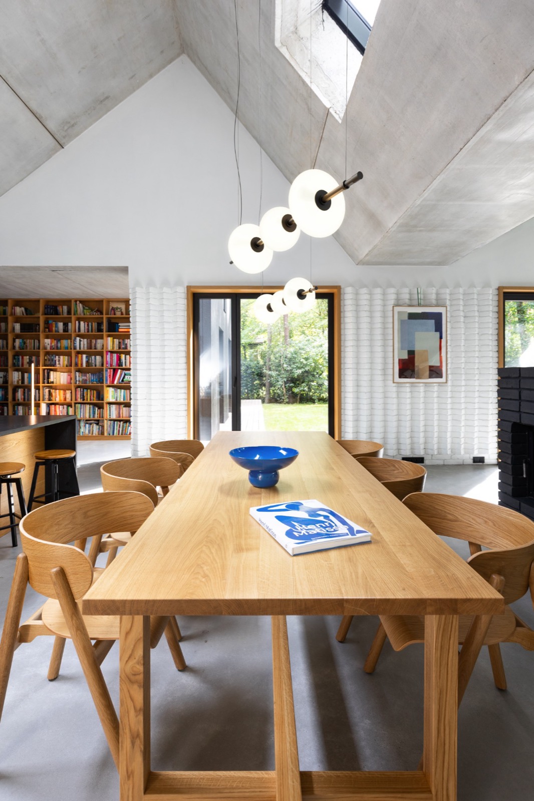 Aqform Beads linear pendant over an oak dining table in a concrete-vaulted interior