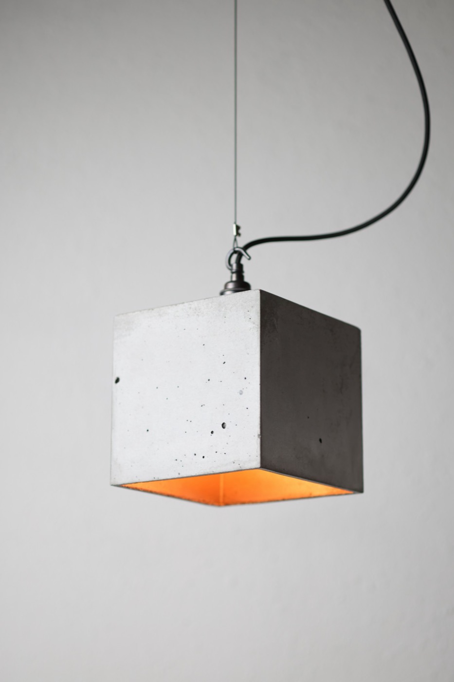 Cube-shaped concrete pendant with a warm glowing interior