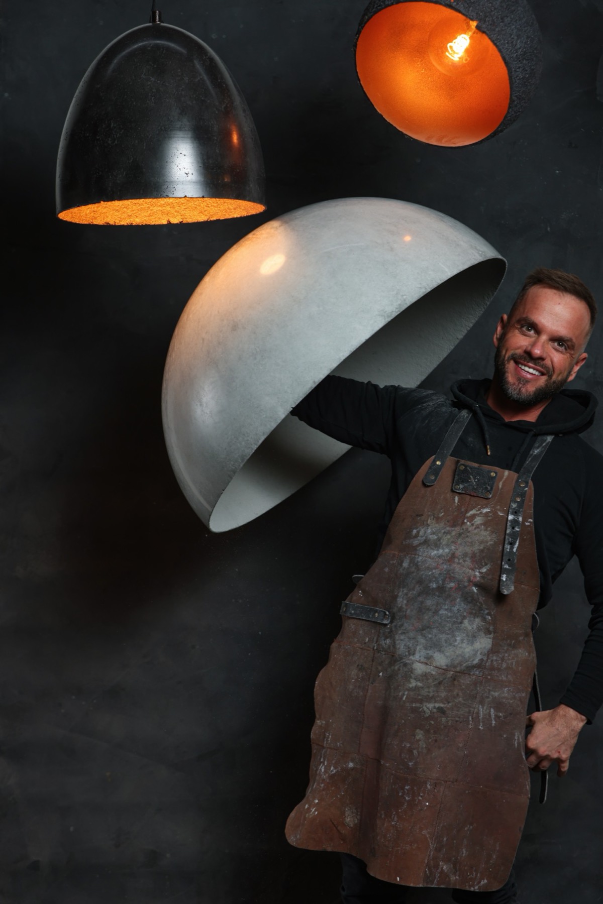 Sowa Stone's founder holding a large concrete dome shade in one hand