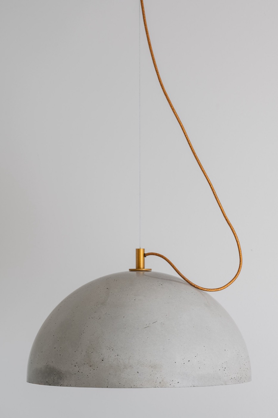 Grey concrete hemisphere pendant with a gold-tone fitting and braided copper cable