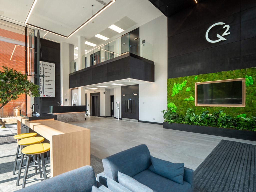 2 Whitehall Quay — full reception area with coffee bar, seating, and double-height bespoke linear LED lighting