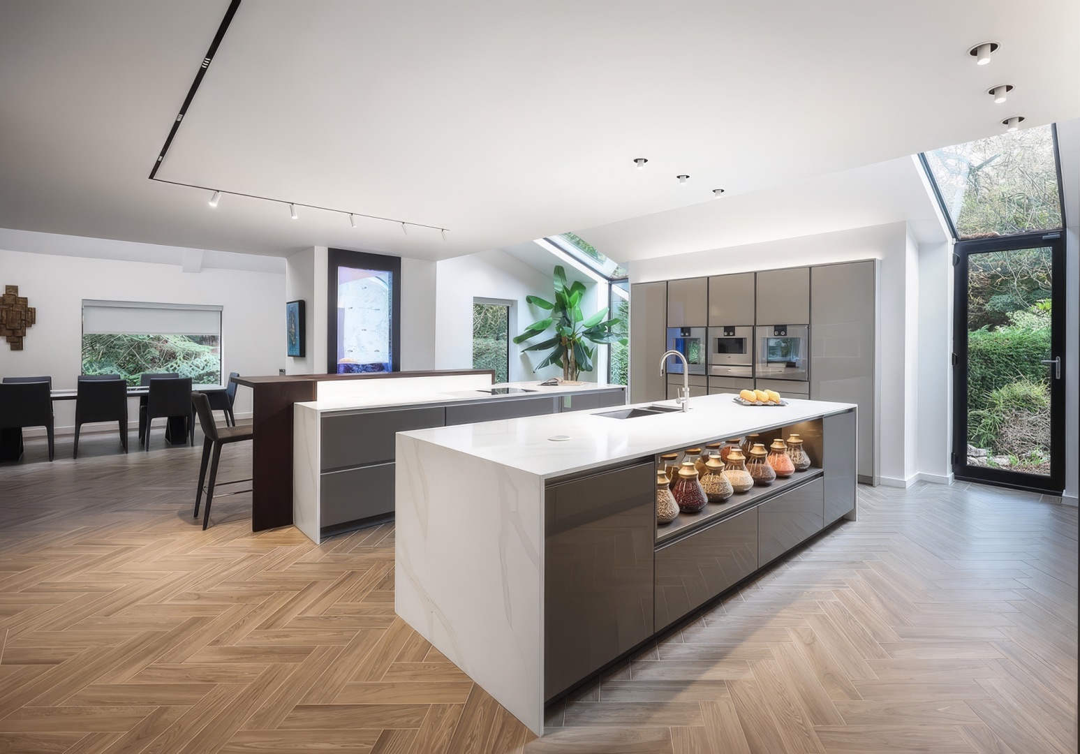 Private residence Bolton — kitchen island and dining zone with Deltalight Splitline track and Spy luminaires