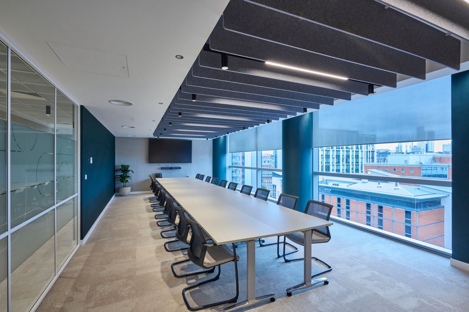 Boardroom with low-glare spotlights and linear light within the acoustic baffles, overlooking Leeds