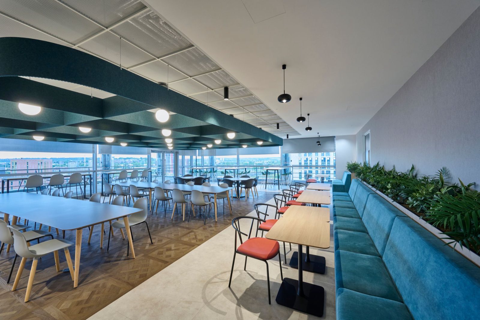 Staff dining area with globe lights set into a green acoustic ceiling grid and pendants over banquette seating