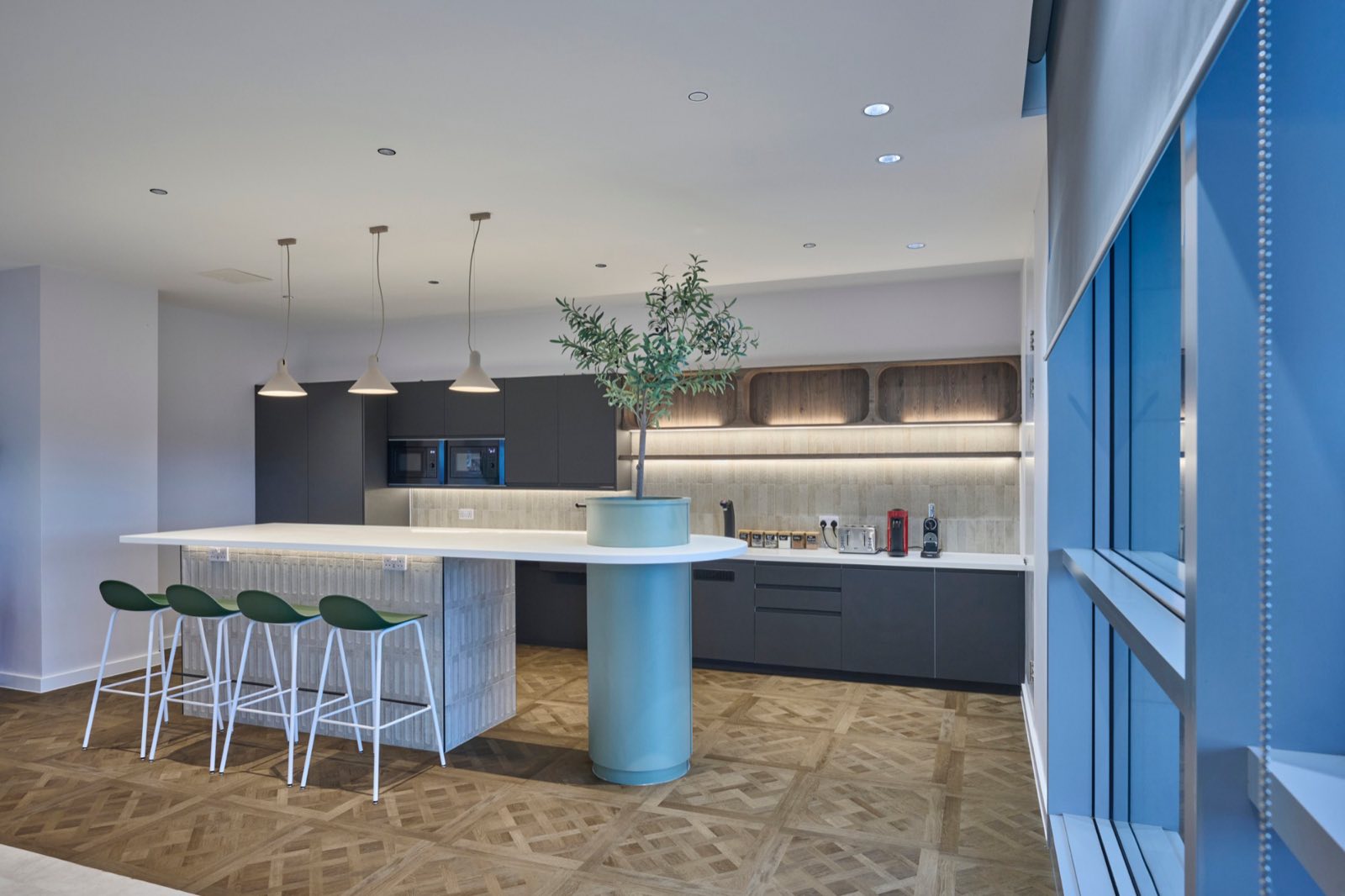 Staff kitchen with Aqform pendants over the island and warm under-shelf lighting